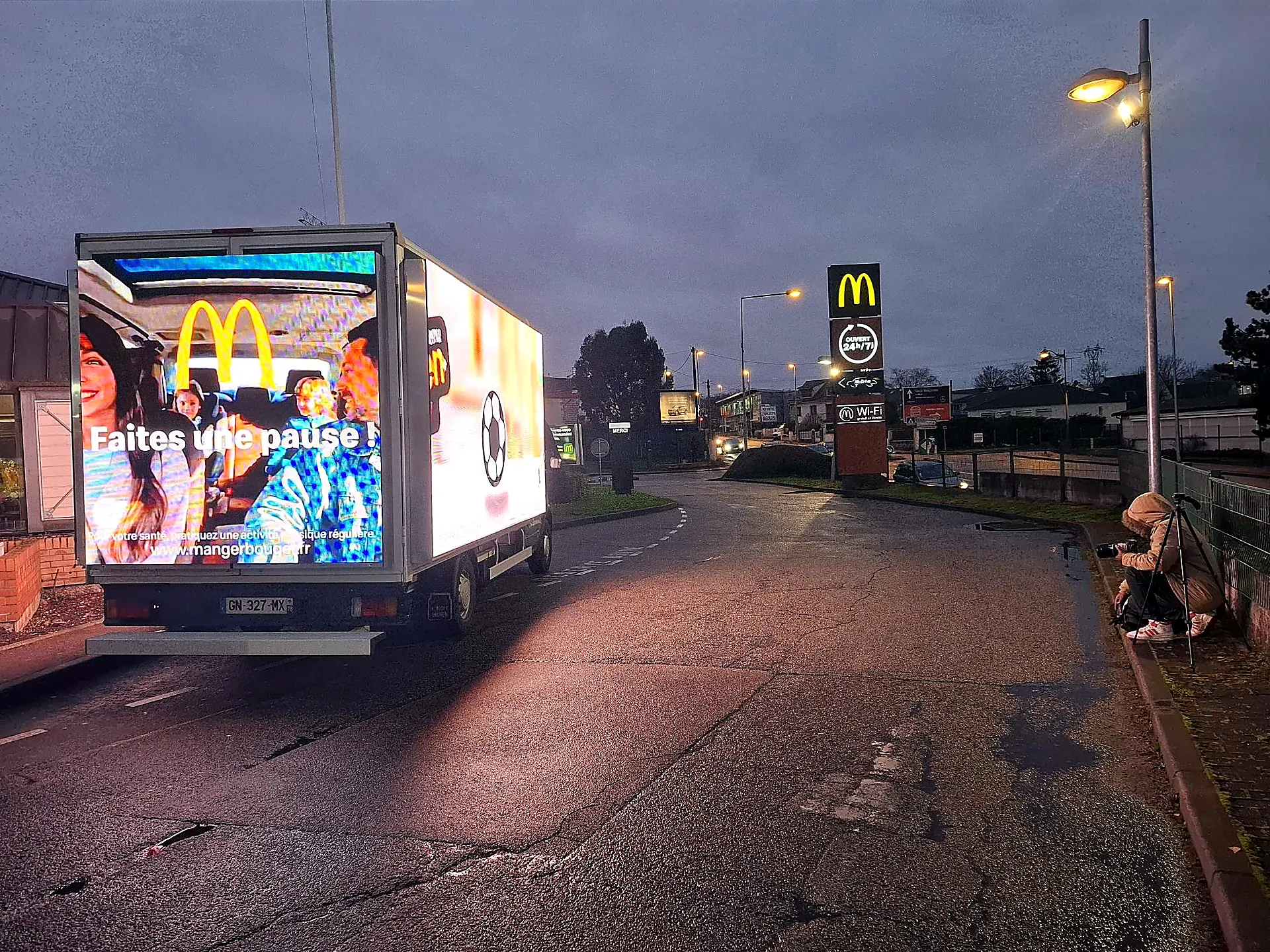 Camion LED près d'un restaurant McDonald's au crépuscule, un photographe documente la campagne